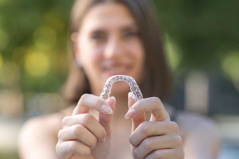 mujer sosteniendo ortodoncia invisible